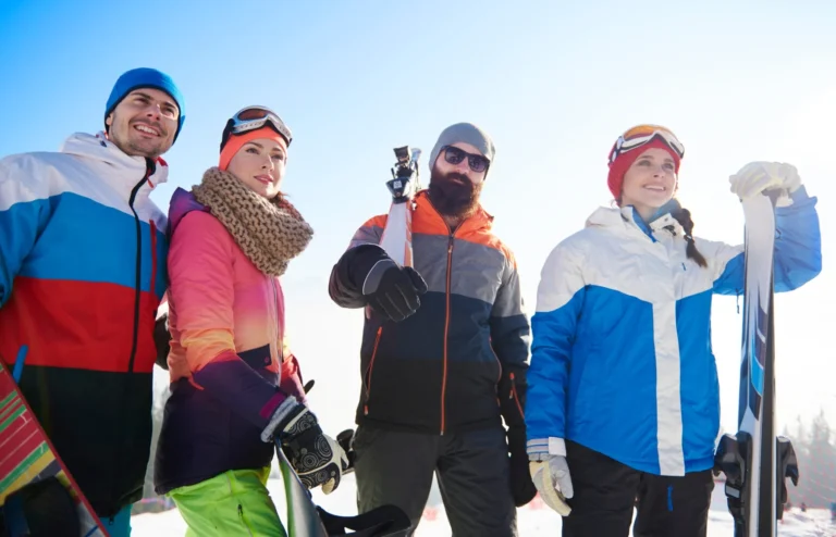 Happy mates with snowboards and skis