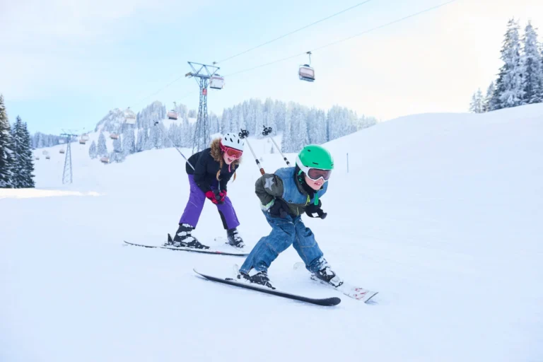 Teenage girl and brother skiing down ski slope, Gstaad, Switzerland