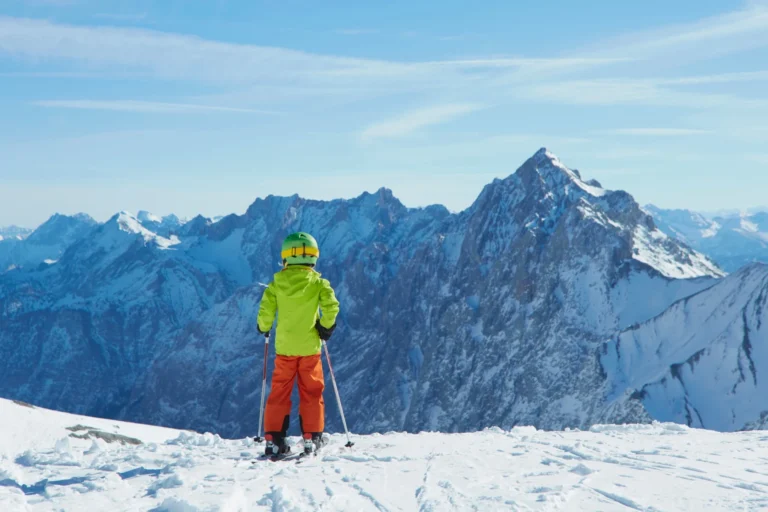 Young boy at edge of mountain, ready to ski down, rear view